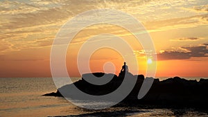 Meditation on the rocks, a man sitting on a rock in the sea at sunset