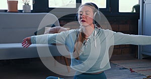 Meditation smart phone app. Beautiful sporty slim young blonde woman relaxing at home in headphones on self isolation.