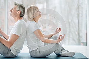 Meditation together.Cropped picture of senior couple doing yoga together in the white gym. Health and sport concept