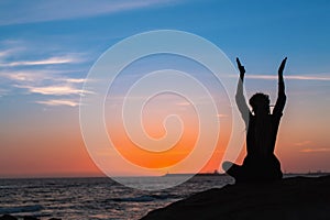 Meditation woman yoga silhouette. Sea during amazing sunset.