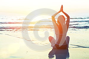 Meditation yoga woman silhouette on the background of the sea and amazing sunset