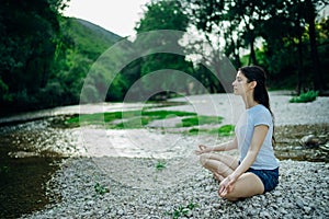 Meditation yoga woman siting at Lotus position on the shore of river.Serenity and yoga practice.Healthy lifestyle.Self isolation