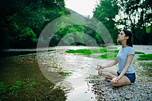 Meditation yoga woman siting at Lotus position on the shore of river.Serenity and yoga practice.Healthy lifestyle.Self isolation