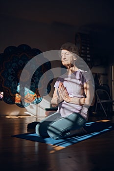 Meditation, zen and elderly woman doing yoga in dark room, shadow and positive energy, balance and mindfulness. Wellness