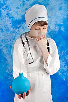 Meditative boy in doctor's costume holding enema