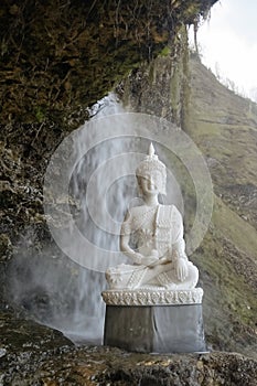 Meditative Buddha statue with a waterfall and beautiful natural setting