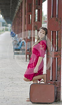 Meditative girl with suitcase waiting at the train station