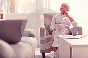 Meditative well-dressed senior lady chilling at home