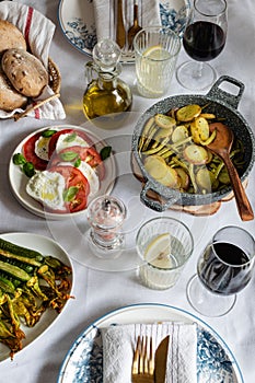 Mediterranean cuisine, served dinner, burrata cheese, olive oil, tomato, stuffed potato, zucchini and red wine