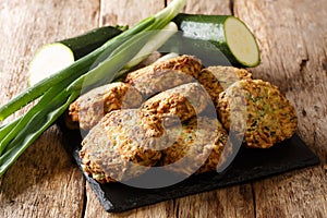 Mediterranean cuisine zucchini fritters with feta cheese close-up on a slate board. Horizontal