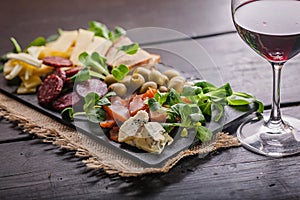 Mediterranean delicious and tasty snacks. Assorted cheeses, sausages, smoked meat, lettuce, bread, olives, glass of red wine and