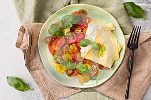 Mediterranean diet, veggies, tomatoes, basil, omlete and buratta on green plate