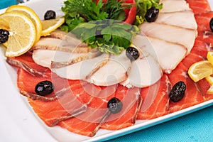 Mediterranean fish sliced â€‹â€‹salmon, tuna and trout with vegetables, greens, lemon and black olives