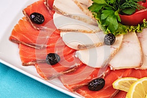 Mediterranean fish sliced â€‹â€‹salmon, tuna and trout with vegetables, greens, lemon and black olives