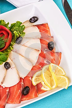 Mediterranean fish sliced â€‹â€‹salmon, tuna and trout with vegetables, greens, lemon and black olives