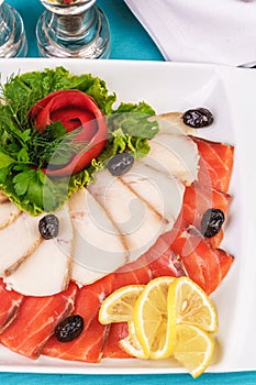 Mediterranean fish sliced â€‹â€‹salmon, tuna and trout with vegetables, greens, lemon and black olives