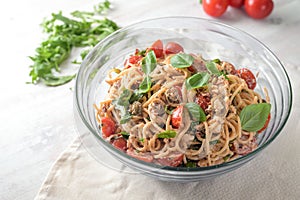 Mediterranean party salad from spaghetti with tomatoes, arugula, mozzarella, olives and basil in a glas bowl on a white painted