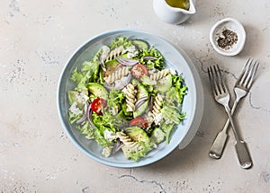 Mediterranean pasta avocado salad on a light background, top view. Vegetarian diet food concept