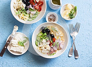 Mediterranean pasta salad. Pasta farfalle, tomatoes, cucumbers, olives, feta cheese and arugula salad. On a blue background, top