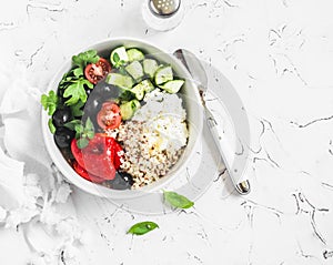 Mediterranean quinoa bowl with avocado, cucumbers, olives, roasted pepper, feta cheese, arugula. On a white background.