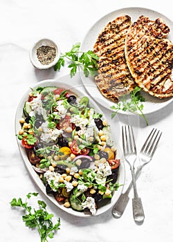 Mediterranean style lunch table - Greek chickpeas salad and pork chops on light background, top view