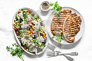 Mediterranean style lunch table - Greek chickpeas salad and pork chops on light background, top view