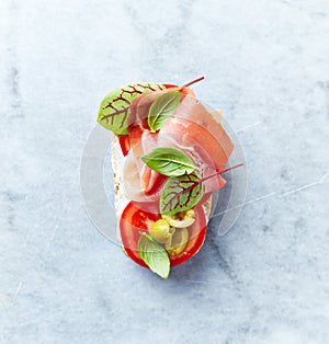 Mediterranean-style open sandwich with Serrano Ham, Tomato, Gren Olives, Basil leaves and Red Sorrel