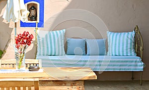 Mediterranean style terrace with wooden table, chair, flowers and sofa on a backdrop
