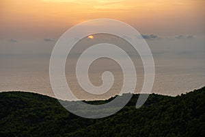 Mediterranean sunset from the Agalas viewpoint. Sitting and watching sunset in Zakynthos, Greece. Sunset pine trees, olive groves