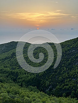 Mediterranean sunset from the Agalas viewpoint. Sitting and watching sunset in Zakynthos, Greece. Sunset pine trees, olive groves