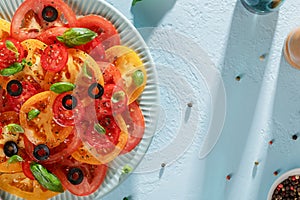 Mediterranean tomato salad in the plate on blue pastel background.