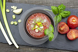 Mediterranean tomato soup in a bowl decorated with spring onions and basil.