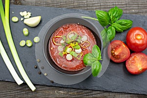 Mediterranean tomato soup with spring onions, pepper and basil. View from above