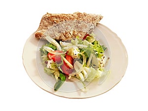 Mediterranean vegetable salad with smooth slices of homemade bread spread out on the edge of the plate. Veggirarian dish on