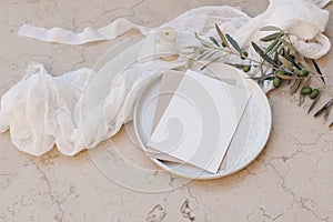 Mediterranean wedding stationery. Greeting card, invitation mock up. Envelope on plate.Beige marble background. Olive