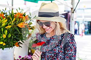 Mediterranean woman in hat holding gerbera and looking down