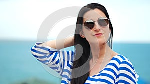 Medium close-up of fashionable touristic woman wearing sunglasses at sea sky natural background