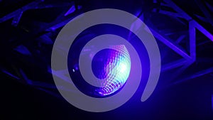 Medium close up of a live disco ball in a night club with flashing lights