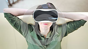 Medium close-up pleased woman wearing modern virtual reality mask and relaxing