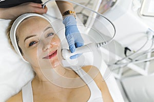 medium closeup view of a beautiful Caucasian woman having a face massage procedure at the cosmetology center, beauty
