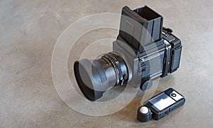 Medium format vintage film camera and exposure meter on gray concrete loft style background