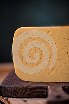 Medium hard cheese gouda edam on wooden board on sunlight table traditional table texture