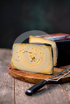 Medium hard cheese head gouda edam on wooden board with knife wooden texture daylight