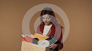 Medium isolated shot of a sad, tearful and pity young woman holding a box with her belongings from the office and
