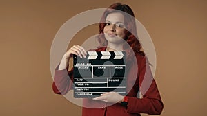 Medium isolated shot satisfied, happy and relaxed young woman holding a closed movie clicker, slate, clapperboard in
