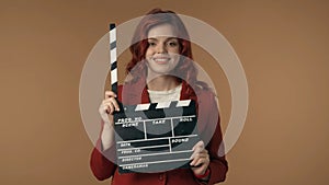 Medium isolated shot satisfied, happy and relaxed young woman holding an opened movie clicker, slate, clapperboard in