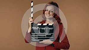 Medium isolated shot satisfied, happy and relaxed young woman holding an opened movie clicker, slate, clapperboard in