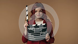 Medium isolated video satisfied, happy and relaxed young woman holding a movie clicker, slate, clapperboard in front of