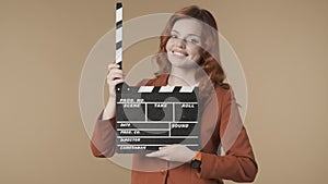 Medium isolated video satisfied, happy and relaxed young woman holding a movie clicker, slate, clapperboard in front of