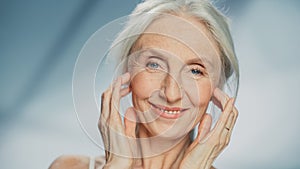 Medium Portrait: Senior Woman Looking at Camera, Touching, Massaging Beautiful Face, Smiling. Elde